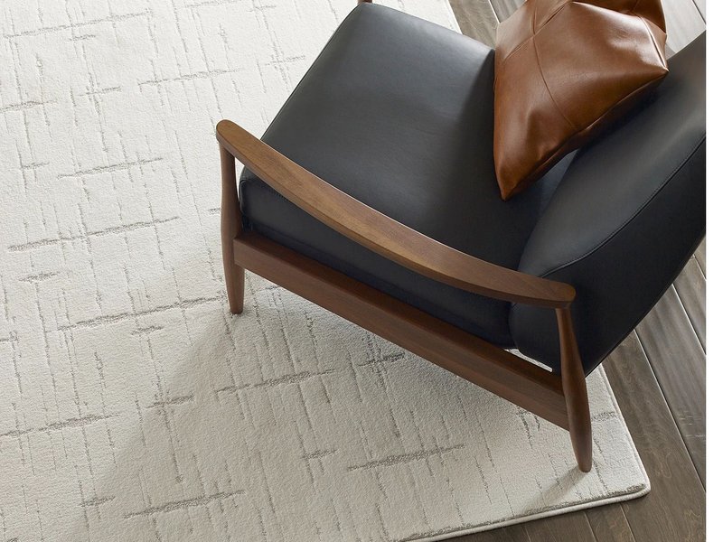 Room with hardwood flooring and a large white area rug with a black armchair on it from River City Flooring in Missoula, MT